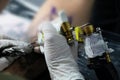 A tattoo artist fills a drawing on a man`s hand with a typewriter. The concept of overcoming pain, courage, creativity and