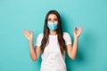 Concept of pandemic, covid-19 and social distancing. Pretty modern woman in white t-shirt and medical mask, showing okay Royalty Free Stock Photo