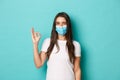 Concept of pandemic, covid-19 and social distancing. Pretty modern woman in white t-shirt and medical mask, showing okay Royalty Free Stock Photo