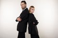 Concept of partnership in business. Handsome man and beautiful woman, both in black suits standing back to back with Royalty Free Stock Photo