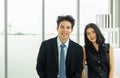 Concept of partnership in business. a man in a suit and a woman in a black dress standing in the office looking at the camera Royalty Free Stock Photo