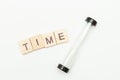 The concept of the passage of time. Inscription made of wooden blocks TIME and hourglass on a white background. Top view