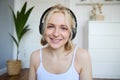 Concept of people and lifestyle, Close up of beautiful blond woman in wireless headphones, listens to music, enjoys good Royalty Free Stock Photo