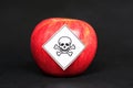 Concept of pesticide residues in agricultural food products dangerous to humans, showing a red apple with poison symbol