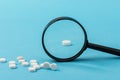 Concept - pharmaceutical testing, testing of medicines, magnifying glass, tablets on a blue background. Doping control Royalty Free Stock Photo