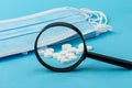 Concept - pharmaceutical testing, testing of medicines, magnifying glass, tablets on a blue background. Doping control Royalty Free Stock Photo