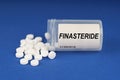 On a blue surface are pills and a dusty jar with the inscription - Finasteride