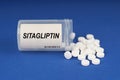 On a blue surface are pills and a dusty jar with the inscription - Sitagliptin