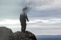 A concept photo of a hooded figure standing on a hill as his head disintegrates into the air.