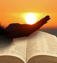 Holding sun in hand with open holy bible Royalty Free Stock Photo