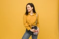 Concept photo of young female with purse, smiling and looks happy. Wears yellow shirt, isolated yellow color background