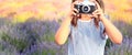 The concept of photography. Girl in a striped dress holds a camera in her hands and shoots a summer landscape against a background