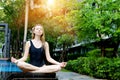 Strong woman sitting in lotus position, doing yoga by the pool on a sunny day Royalty Free Stock Photo