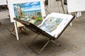 Opened easel briefcase with work of a street artist inside. Exhibition where painters sell their paintings
