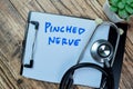 Concept of Pinched Nerve write on paperwork with stethoscope isolated on Wooden Table