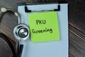 Concept of PKU Screening write on sticky notes with stethoscope isolated on Wooden Table Royalty Free Stock Photo