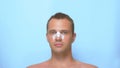 Concept of plastic surgery, a man after a plastic surgery on the face, rhinoplasty, with a bandage on the nose. on blue
