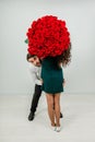 Funny couple joking and fooling with bouquet of red roses over white background. Royalty Free Stock Photo