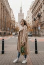 Concept of Poland lifestyle and travel towns in Warsaw. Young beautiful woman walking with bouguet of tulips on Warsaw