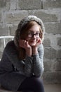 Concept portrait of a pleasant friendly happy teenager in glasses on chair. Young girl is sitting in a gray dress and smiling