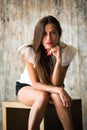 Concept portrait of pretty beautiful brunette girl on grey background in Studio sitting on cube in front of camera Royalty Free Stock Photo