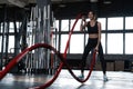 Powerful attractive muscular woman CrossFit trainer do battle workout with ropes at the gym Royalty Free Stock Photo