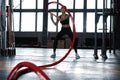 Powerful attractive muscular woman CrossFit trainer do battle workout with ropes at the gym Royalty Free Stock Photo