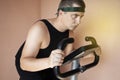 Cheerful fat man in a funny tracksuit is engaged in a stationary bike. The concept of problems with weight, losing weight, playing Royalty Free Stock Photo