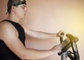 Cheerful fat man in a funny tracksuit is engaged in a stationary bike. The concept of problems with weight, losing weight, playing Royalty Free Stock Photo