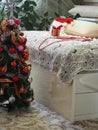 The concept of the process of decorating a Christmas tree in red style.A bed with a gift, beads and a Santa Claus hat on