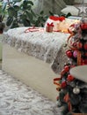 The concept of the process of decorating a Christmas tree in red style.A bed with a gift, beads and a Santa Claus hat on the bed