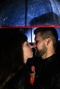 A couple in love under an umbrella kissing, and rain is falling on them. Night photography of people. The concept of protecting Royalty Free Stock Photo