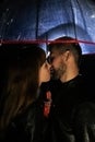 A couple in love under an umbrella kissing, and rain is falling on them. Night photography of people. The concept of protecting Royalty Free Stock Photo