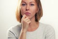 The concept of psychology and emotions. A young blonde woman leans her cheek on her hand, and looks thoughtfully. White background