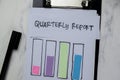 Concept of Quarterly Report write on paperwork and bar graph isolated on Wooden Table Royalty Free Stock Photo