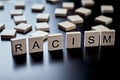 Concept of racism and misunderstanding between people, prejudice and discrimination. Wooden block with word racism on the black