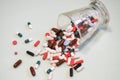 Many drugs and pills spilled out of a glass on a light background. Royalty Free Stock Photo