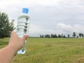 The concept of receiving clean drinking water in everyday life in the open air. In my hand, the bottle is transparent.