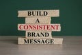 Concept red words build a consistent brand message on brick blocks. Beautiful green background, wooden table. Business consistent