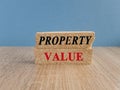 Concept red words Property value on brick blocks. Beautiful wooden table blue background. Business property value concept. Copy