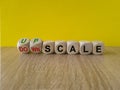 Concept red words Upscale or Downscale on wooden cubes. Beautiful wooden table yellow background. Business upscale or downscale