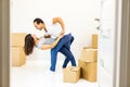 Picture of a cheerful couple dancing after moving into their new apartment with piles of cardboard boxes. Door blurred