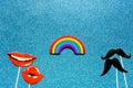 Concept of relationships between same-sex men and women, flatlay false photo stand props mustache and lips rainbow on a blue shiny