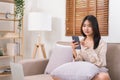 Concept of relaxation at home, Young Asian woman use smartphone to chatting with friends on sofa Royalty Free Stock Photo