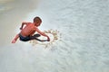 Concept of relaxation at summer sea. Cute boy on seashore paints smiling sun on sand. Child paints smiley face Top view copy space