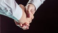 Concept of a reliable partnership: a close-up of handshake of business partners on black background. Royalty Free Stock Photo