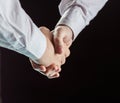 Concept of a reliable partnership: a close-up of handshake of business partners on black background. Royalty Free Stock Photo