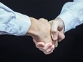 Concept of a reliable partnership: a close-up of handshake of business partners on a black background. Royalty Free Stock Photo