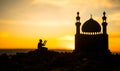 Concept of religion Islam. Silhouette of man praying on the background of a mosque at sunset