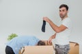 Wife and husband are busy, unpacking the carton boxes. Man is standing. holding black sock, looking at the camera with Royalty Free Stock Photo
